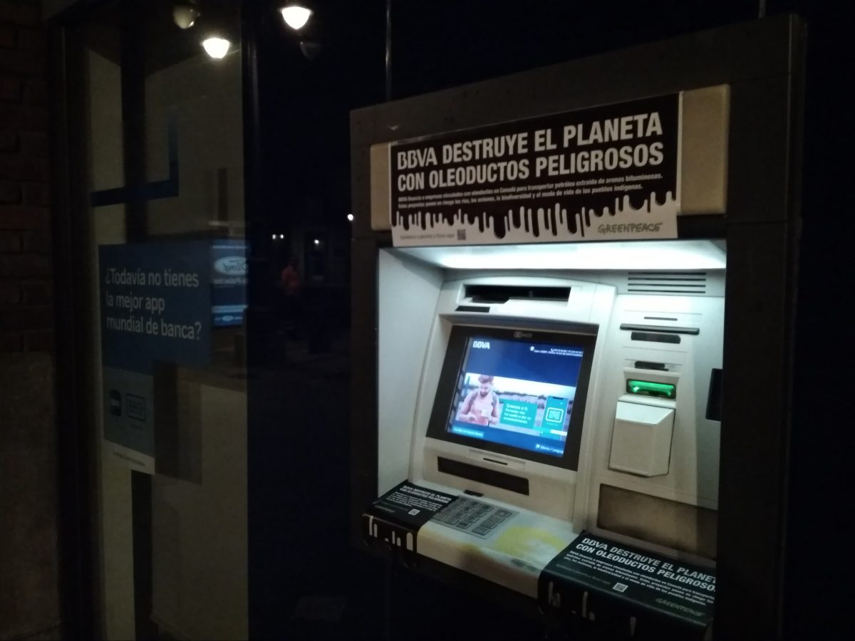 Cajero del BBVA en León con pegatinas que dicen BBVA destruye el planeta con oleoductos peligrosos
